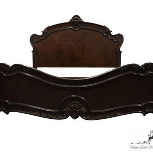 May include: A dark wood carved bed frame with a headboard featuring intricate details and a curved design. The bed frame is a traditional style with a classic look.