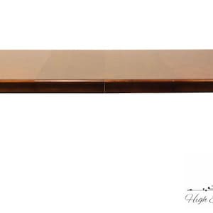 May include: A brown wooden dining table with a rectangular top and four cabriole legs. The table has a leaf that can be added to extend the length.