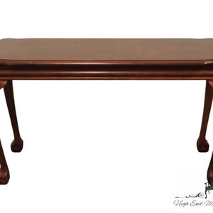 May include: A dark brown wooden coffee table with a rectangular top and four cabriole legs. The table has a slightly rounded edge and a simple design.