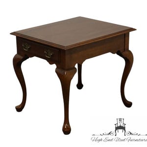 May include: A dark brown wooden end table with a single drawer and cabriole legs. The table has a simple, elegant design.