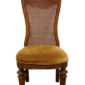 May include: A wooden dining chair with a cane back and a brown velvet seat. The chair has a carved design on the back and legs.