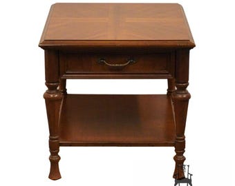 May include: A dark wood end table with a single drawer and a lower shelf. The table has turned legs and a simple design.