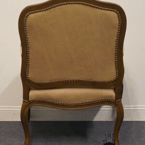 Puede incluir: Una silla de madera marr&oacute;n con un asiento y respaldo tapizados en beige. La silla tiene un respaldo curvo y detalles ornamentados en las patas.