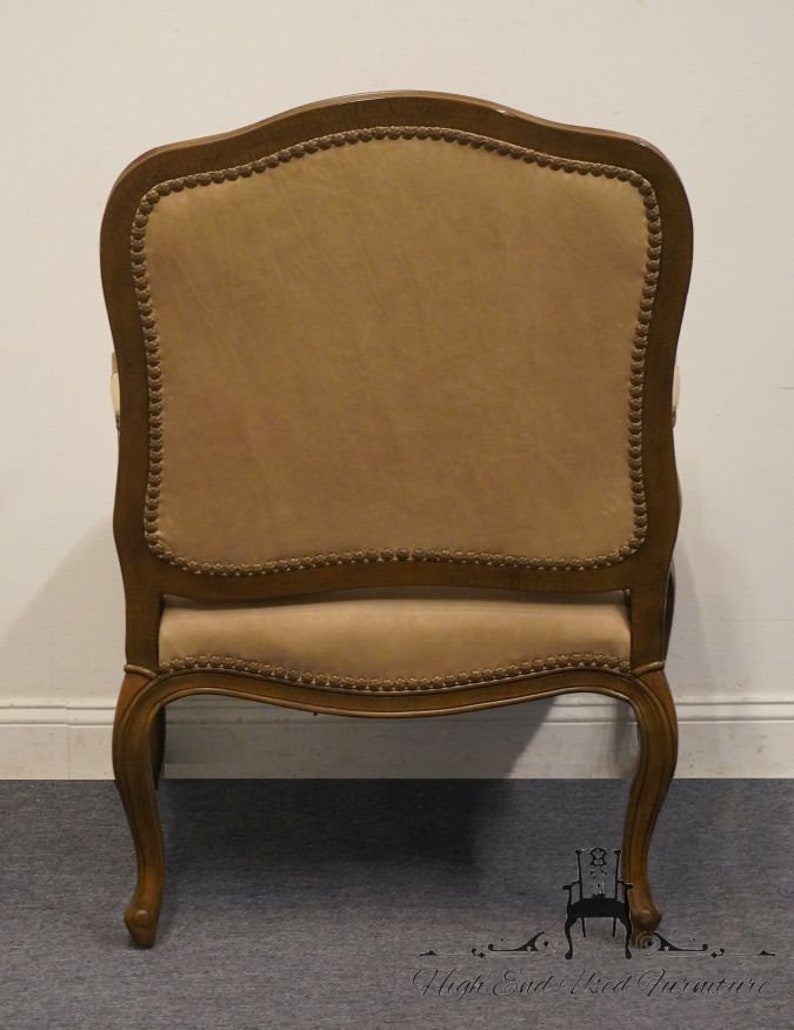 Puede incluir: Una silla de madera marr&oacute;n con un asiento y respaldo tapizados en beige. La silla tiene un respaldo curvo y detalles ornamentados en las patas.