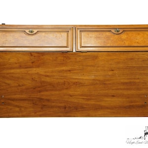 May include: A vintage wooden secretary desk with two drawers and a drop-down front. The desk is made of a rich brown wood with a wood grain pattern. The desk has brass hardware and a simple design.