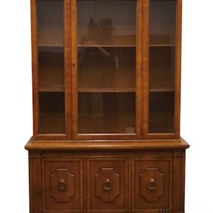 May include: A wooden hutch with glass doors and three drawers. The hutch has a dark wood finish and brass hardware.