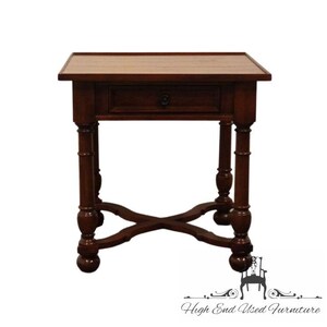 May include: A dark brown wooden end table with a single drawer and turned legs. The table has a cross-shaped base and a rectangular top.