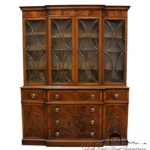 May include: A large, antique wooden cabinet with glass-paned doors and drawers. The cabinet is made of dark wood with a detailed grain pattern. The upper section has glass doors with decorative metal accents. The lower section features drawers with brass knobs.