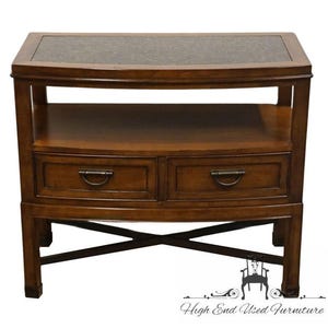 May include: A dark brown wooden side table with a dark speckled top. The table has two drawers with metal handles and a lower shelf. The legs are connected by an X-shaped support.
