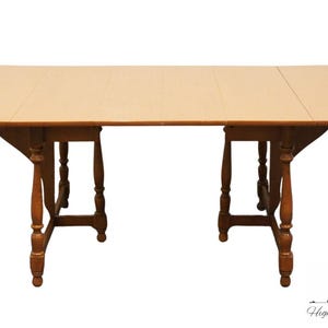 May include: A light wood drop leaf table with a rectangular top and two sets of turned legs. The table is closed and ready for use.