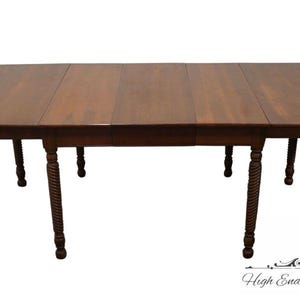 May include: A dark brown wooden table with a drop leaf design and turned legs. The table is made of solid wood and has a rich, warm finish.