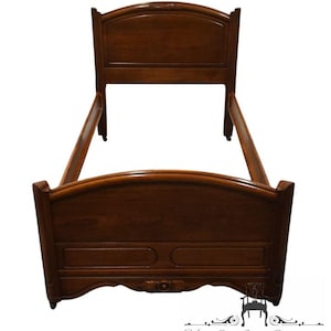 May include: A wooden twin-size bed frame with a curved headboard and footboard. The frame is made of dark wood and has a simple, elegant design.