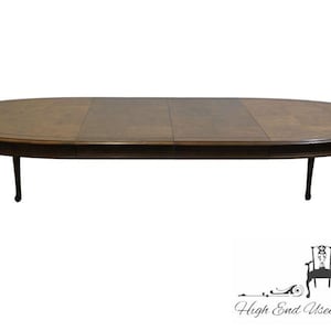May include: Oval wooden dining table with a dark brown finish. The table has a detailed edge and four curved legs. The table is approximately 72 inches long and 42 inches wide.