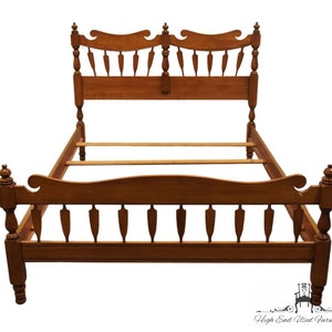 May include: A wooden bed frame with a headboard and footboard. The frame is a warm brown color and features decorative spindles and finials. The headboard has a curved top with a series of vertical cutouts. The footboard mirrors the headboard's design.
