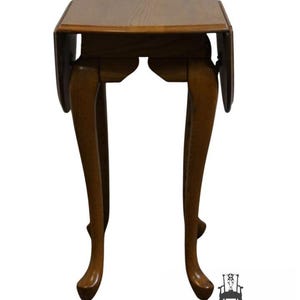 May include: A brown, antique drop-leaf table with a square top and curved legs. The table has a warm, wooden finish and is designed with a classic, elegant style. The table is a vintage piece of furniture.