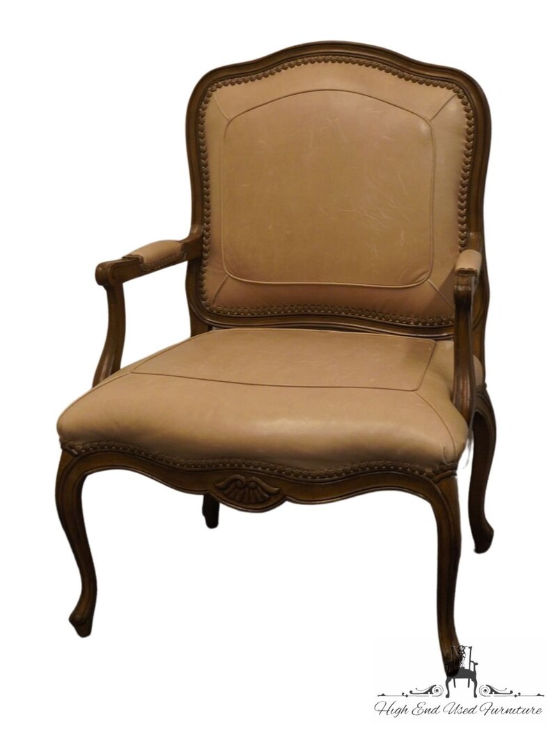 Puede incluir: Un sill&oacute;n de cuero marr&oacute;n con un marco de madera tallada y un respaldo capiton&eacute;. La silla tiene un dise&ntilde;o cl&aacute;sico y ser&iacute;a una gran adici&oacute;n a cualquier sala de estar o comedor.