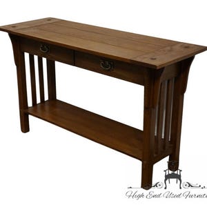 May include: A dark brown wooden console table with two drawers and a lower shelf. The table has a simple, traditional design with a rectangular top and straight legs.