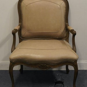 Puede incluir: Un sill&oacute;n de cuero beige con un marco de madera tallada. El sill&oacute;n tiene un respaldo alto y un asiento curvo. El sill&oacute;n est&aacute; en buen estado y ser&iacute;a una gran adici&oacute;n a cualquier hogar.