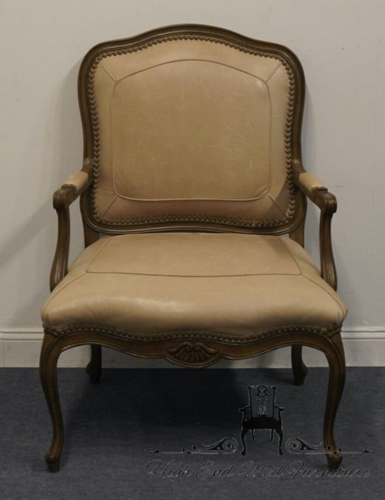 Puede incluir: Un sill&oacute;n de cuero beige con un marco de madera tallada. El sill&oacute;n tiene un respaldo alto y un asiento curvo. El sill&oacute;n est&aacute; en buen estado y ser&iacute;a una gran adici&oacute;n a cualquier hogar.