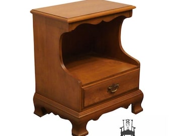 May include: A solid wood nightstand with a single drawer and a shelf. The nightstand has a curved, open shelf and a traditional design with a brown finish.