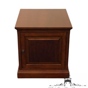 May include: A solid wood end table with a single door and a simple design. The table is a rich brown color and has a slightly raised base.
