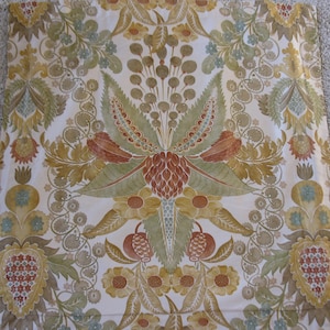May include: Cream-colored fabric with a symmetrical floral pattern in shades of green, brown, and yellow. The design features stylized leaves, flowers, and fruit, creating a vintage or botanical aesthetic. The fabric is likely used for upholstery or decorative purposes.