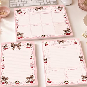 May include: Three pink paper notepads featuring a decorative border with leopard print bows and red cherry illustrations. The set includes a horizontal weekly planner, a vertical lined notepad, and a vertical to-do list with notes and important sections.