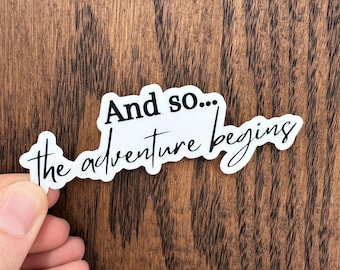 Puede incluir: Pegatina blanca con texto negro que dice "And so... the adventure begins".