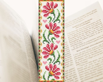 May include: A cross-stitch bookmark featuring a white background with a vertical design of four pink flowers with yellow centres and green stems. The flowers are surrounded by a green and yellow border.