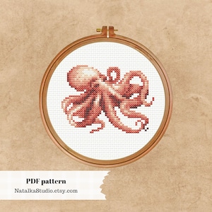 May include: A cross-stitch pattern of an octopus in a wooden embroidery hoop. The octopus is pink and white and is stitched in a realistic style. The pattern is available as a PDF download.