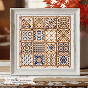 Puede incluir: Un muestrario de punto de cruz enmarcado con una cuadrícula de dieciséis patrones geométricos únicos en azul marino, dorado y blanco. Los patrones incluyen diseños florales y geométricos. El marco es de madera clara. El texto "natalka stitch studio" es visible.