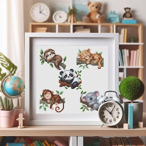 May include: A white framed cross-stitch pattern featuring five sleeping animals: a sloth, a tiger, a panda, a monkey, and a koala. Each animal is depicted on a branch with green leaves.