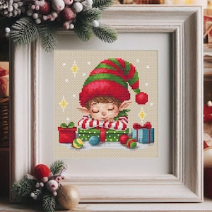 May include: A cross-stitch pattern of a sleeping elf surrounded by presents and ornaments. The elf is wearing a red and green hat and a green and white striped shirt. The presents are wrapped in red, green, and blue paper.