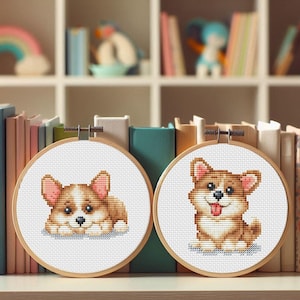May include: Two cross-stitch hoops featuring adorable corgi dog designs. One shows a lying corgi, the other a smiling corgi with its tongue out. The hoops are set against a backdrop of books and shelves.