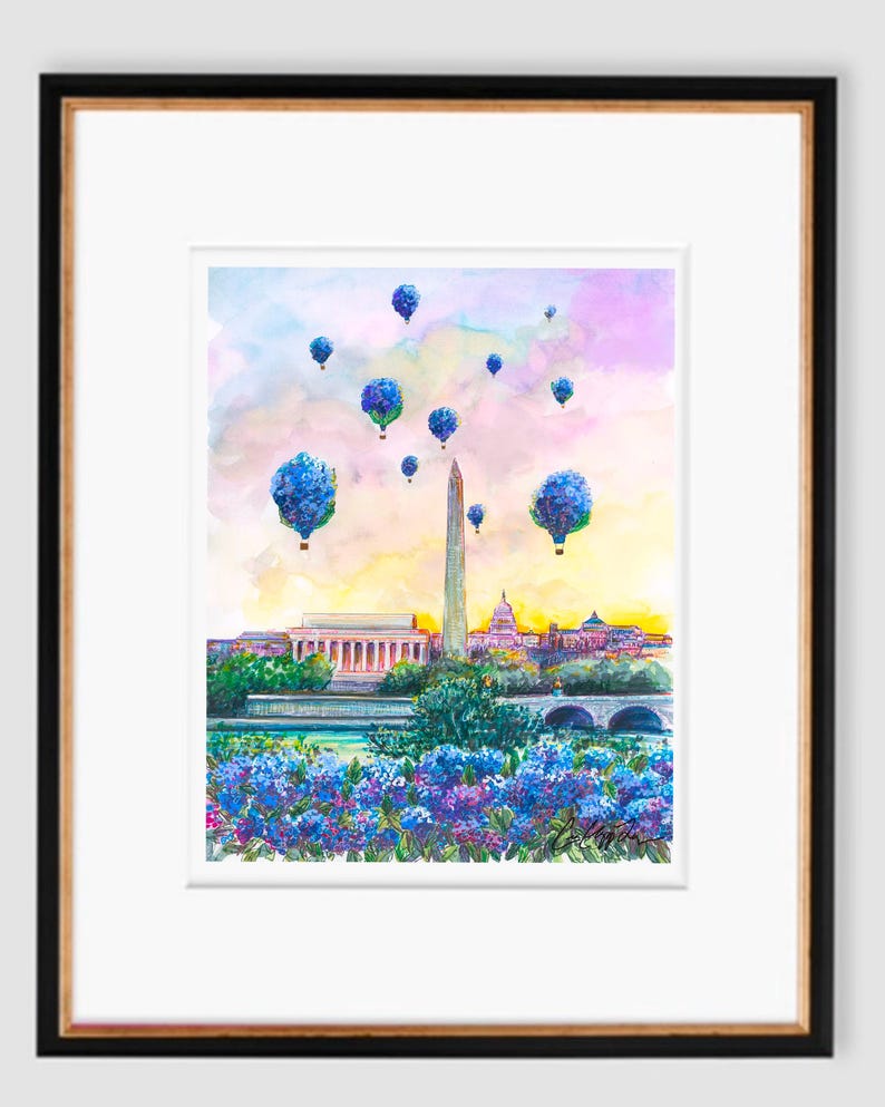 May include: Watercolor painting of the Washington Monument in Washington, D.C. with blue hot air balloons floating in the sky above the city. The painting features a vibrant sunset with pink, orange, and yellow hues. The monument is surrounded by lush green trees and a river.