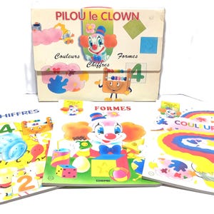 May include: A set of educational materials titled PILOU le CLOWN featuring a storage folder and three books labelled CHIFFRES, FORMES, and COULEURS. The items display colourful illustrations of a clown, geometric shapes, numbers, and rainbows.