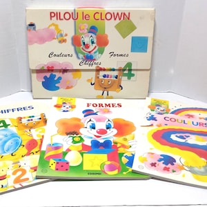 May include: A set of educational materials titled PILOU le CLOWN, including a storage folder and three books labelled CHIFFRES, FORMES, and COULEURS. The items feature colourful illustrations of a clown, numbers, geometric shapes, and rainbows.