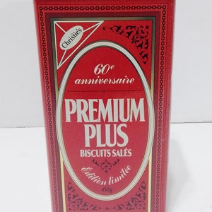 May include: Red metal tin with gold trim featuring a Christie's logo and the text "60e anniversaire PREMIUM PLUS BISCUITS SALÉS Édition limitée 450g".
