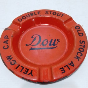 May include: Orange metal ashtray with black lettering that reads "Double Stout Old Stock Ale Yellow Cap Dou"