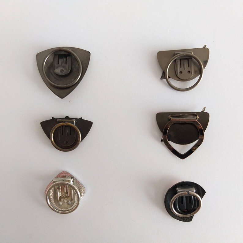 Peut inclure: Six fermoirs m&eacute;talliques diff&eacute;rents de formes et de tailles vari&eacute;es. Les fermoirs sont de couleur argent, noir et or.