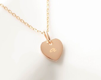 May include: A gold chain necklace with a small heart pendant engraved with the letter "a".