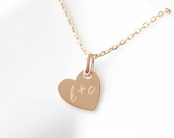 May include: A gold heart-shaped pendant necklace with a delicate chain. The pendant has the initials "L+O" engraved on it.
