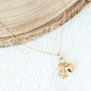May include: A gold chain necklace with a charm featuring a heart, cross, and anchor.