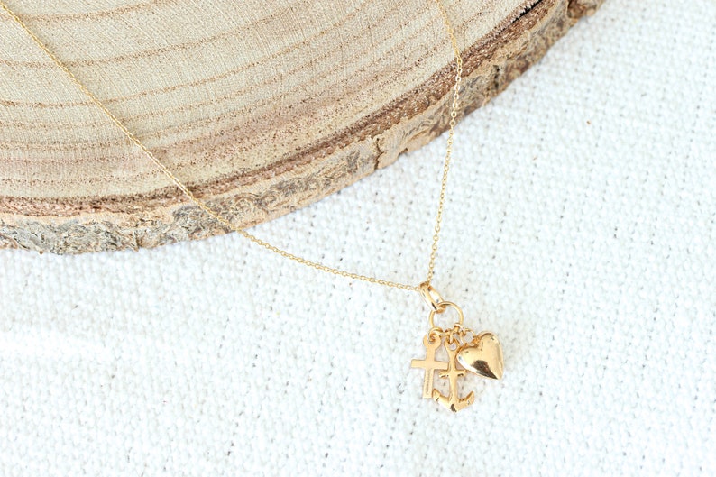 May include: A gold chain necklace with a charm featuring a heart, cross, and anchor.