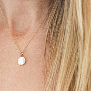 May include: A gold chain necklace with a round white pendant.