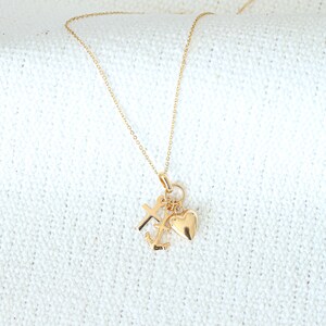 May include: A gold chain necklace with a charm featuring a heart, cross, and anchor.