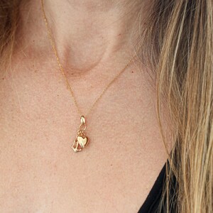 May include: A gold chain necklace with a charm featuring a heart and an anchor.