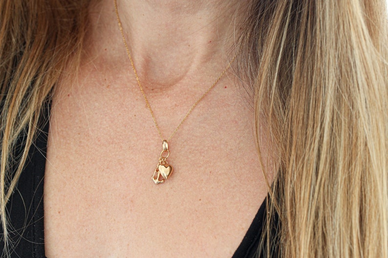 May include: A gold chain necklace with a charm featuring a heart and an anchor.