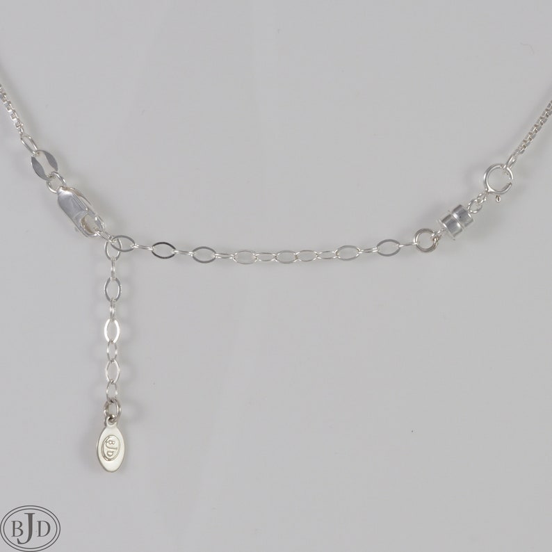 Puede incluir: Collar de cadena de plata con cierre de langosta y una peque&ntilde;a etiqueta ovalada con las letras "BJD" en ella.