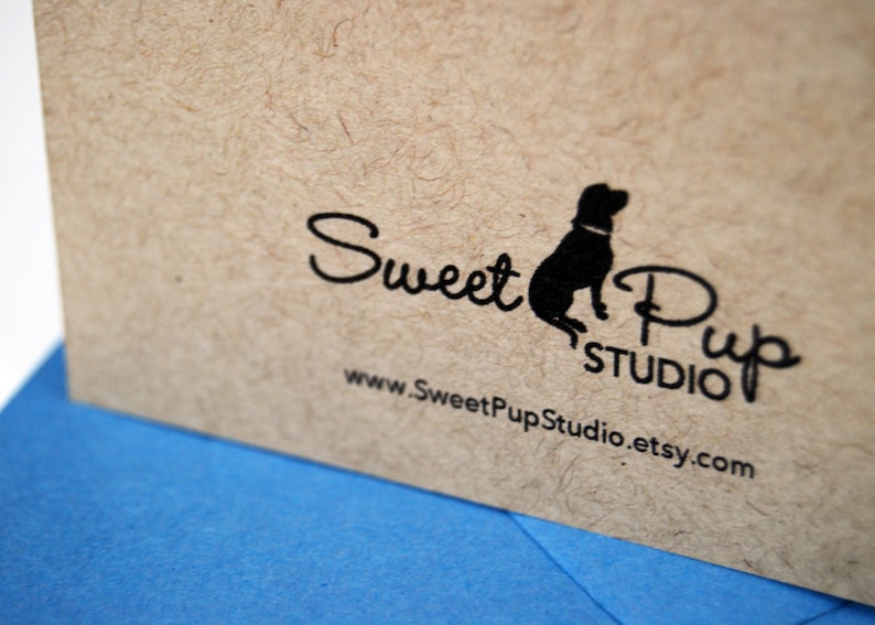 Puede incluir: Primer plano de una tarjeta beige texturizada con el texto negro "Sweet Pup Studio" y una silueta de perro. La direcci&oacute;n del sitio web www.SweetPupStudio.etsy.com tambi&eacute;n est&aacute; impresa en la tarjeta. Una superficie azul es visible en primer plano.